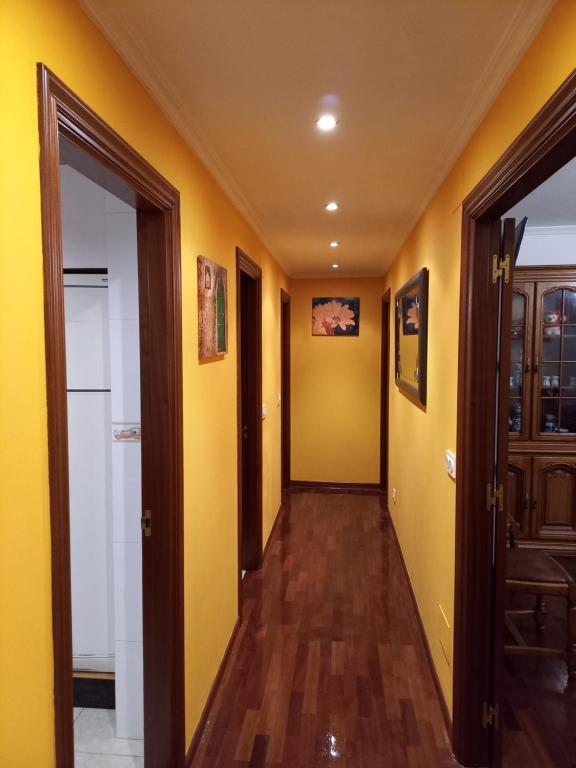 a hallway with yellow walls and wooden floors at Vacaciones in Cedeira