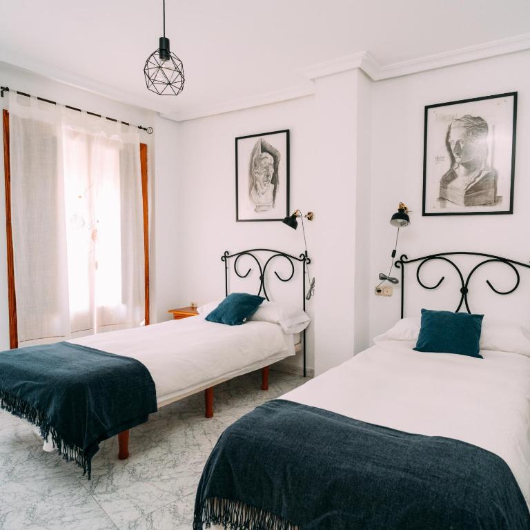 two beds in a bedroom with white walls and blue pillows at LOS VEINTE BALCONES in Caravaca de la Cruz
