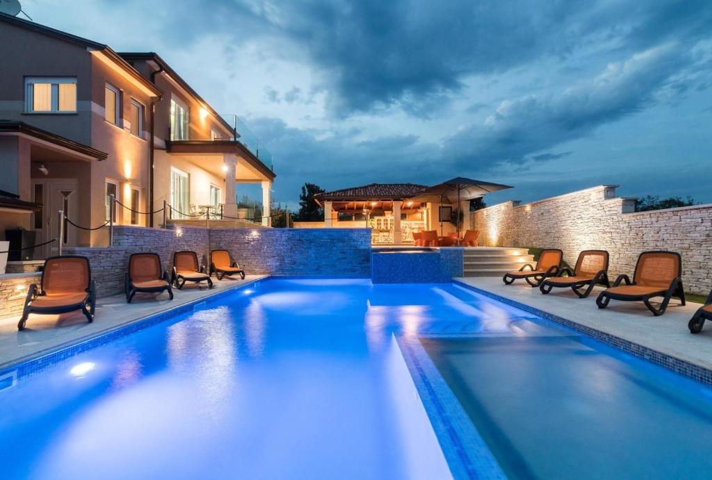 a swimming pool with chairs next to a house at Ferienhaus mit Privatpool für 18 Personen ca 400 qm in Valtura, Istrien Südküste von Istrien in Pula