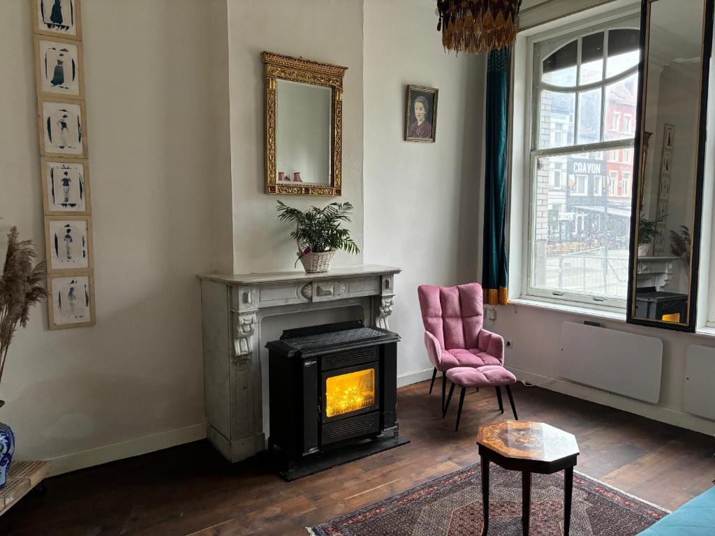 ein Wohnzimmer mit einem Kamin und einem rosa Stuhl in der Unterkunft Belle Epoque flat in the heart of Ostend in Ostende