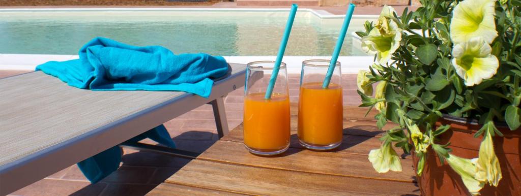 Dois copos de sumo de laranja sentados numa mesa. em Villa con piscina Casale di Giò nel Golfo di Castellammare em Partinico