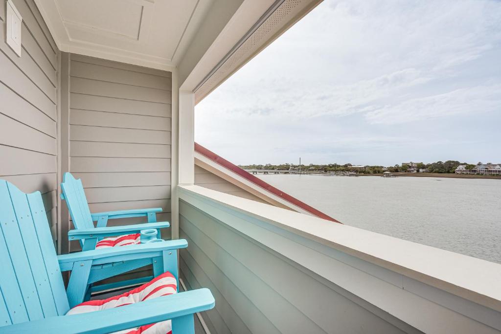 two blue chairs sitting on a balcony overlooking the water at Folly Beach Retreat with Pool Access and River Views! in Folly Beach