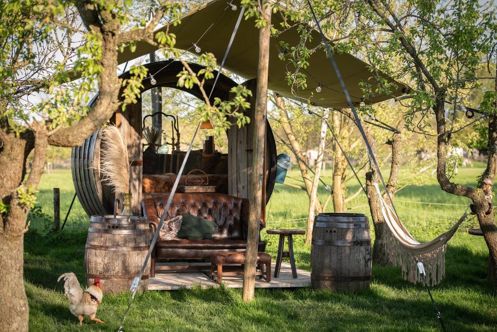 a gazebo with a couch and chickens in a yard at Tiny Wineyhouse 3 in Zennewijnen