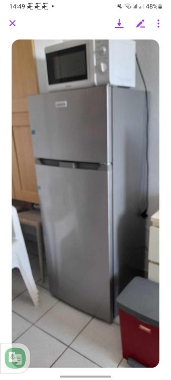 a stainless steel refrigerator in a kitchen with a microwave at Appartement residence le nautile in Le Grau-du-Roi