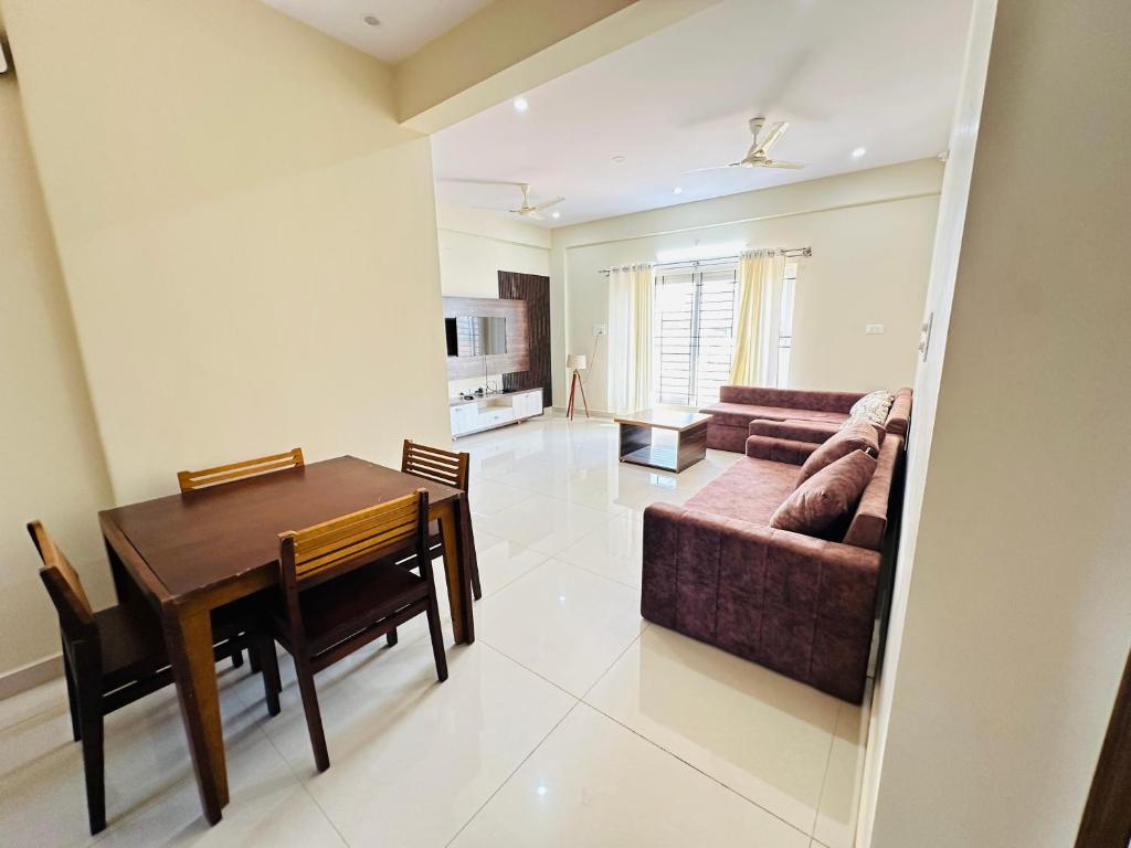 a dining room and living room with a table and a couch at Oryx Residences - Luxury Serviced Apartments in Mysore