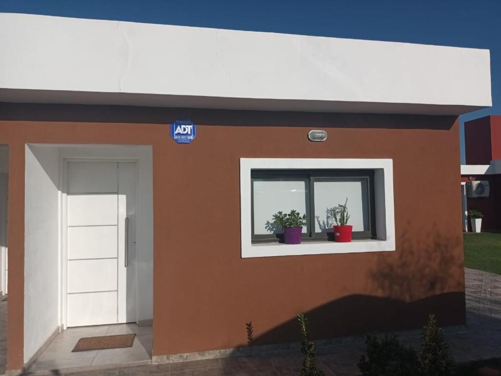 ein Modell eines Hauses mit zwei Topfpflanzen in einem Fenster in der Unterkunft Complejo Bru-Mar 