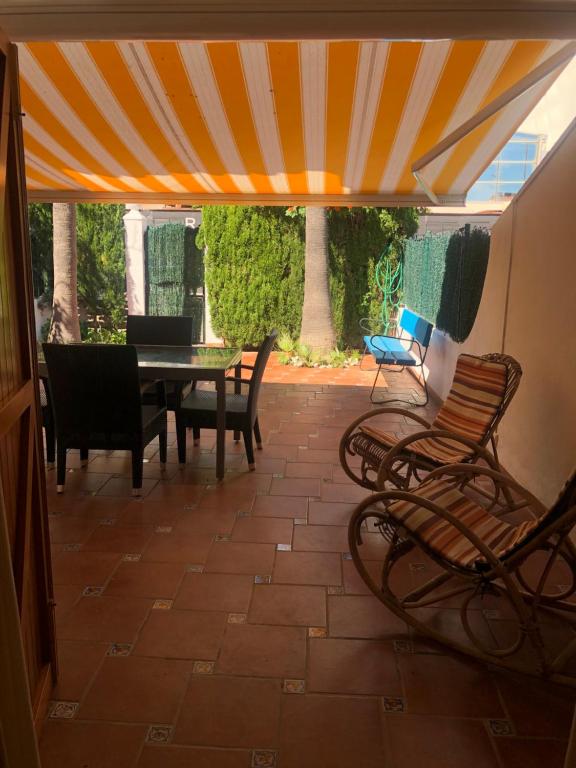 een patio met een tafel en stoelen onder een tent bij Casa adosada Playa de Gandia (2 plantas) in Playa de Gandia