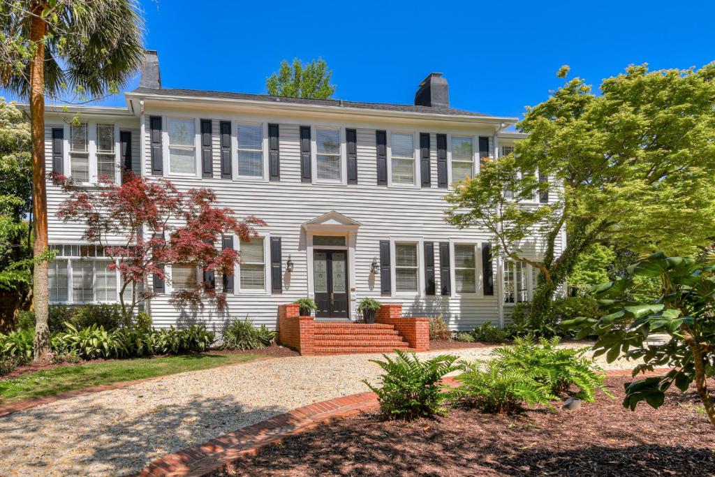 une grande maison blanche avec un palmier dans l'établissement Matchpoint House Aiken, à Aiken