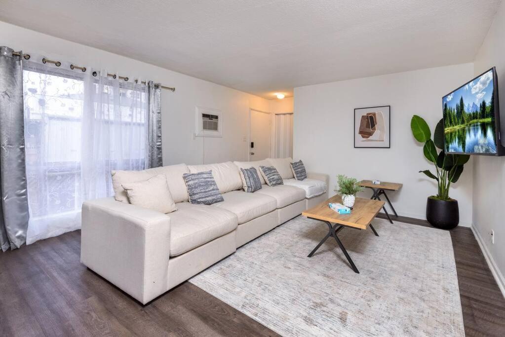 a white living room with a white couch and a tv at LA Paradise: Spacious 3BR Gem with Sleek Interiors in Los Angeles
