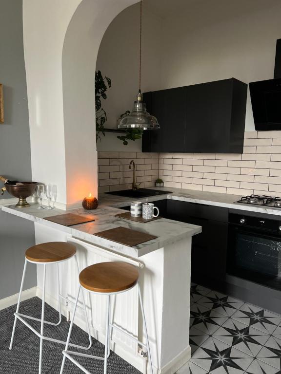 a kitchen with a counter and two stools at Sea Spray Victorian Apartment in St. Leonards