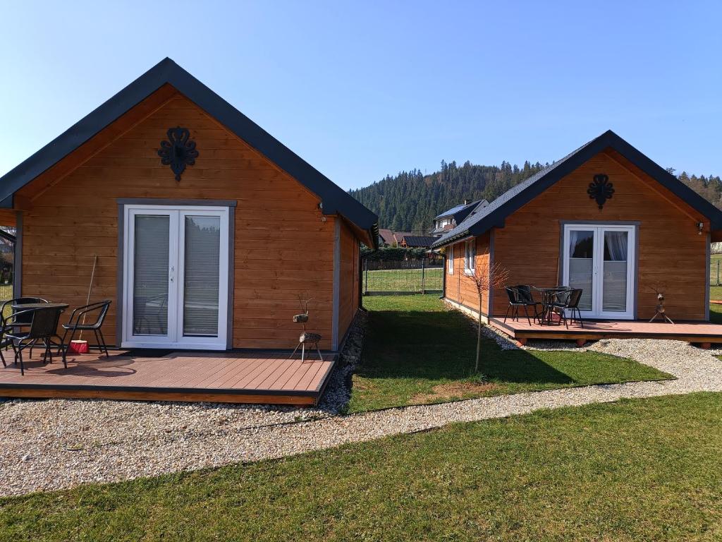 a log cabin with a deck and chairs on it at Spiska Dolina in Łapsze Niżne