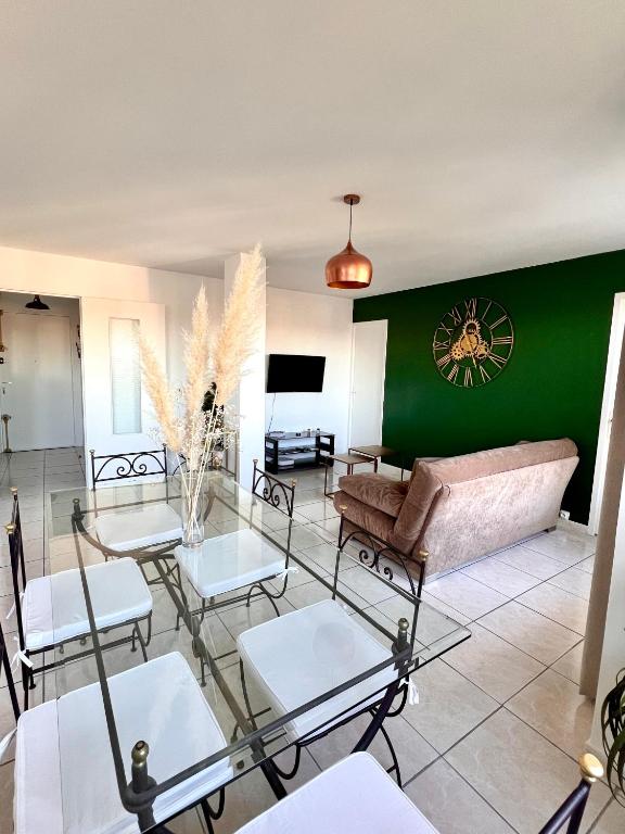 a living room with a couch and tables and a green wall at The Sunrise, Spacious, fully equipped, 2 parkings, 8p, tramway 1,2,4 in Montpellier