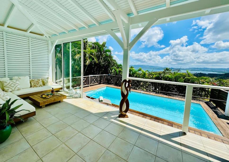 een woonkamer met een zwembad en een patio bij Grande Villa de standing vue mer, piscine 3ilets in Les Trois-Îlets