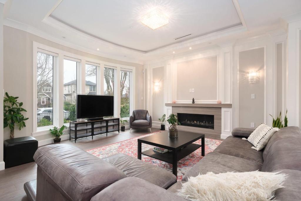 a living room with a couch and a tv at Luxurious 6-Bedroom Mansion Near UBC in Vancouver