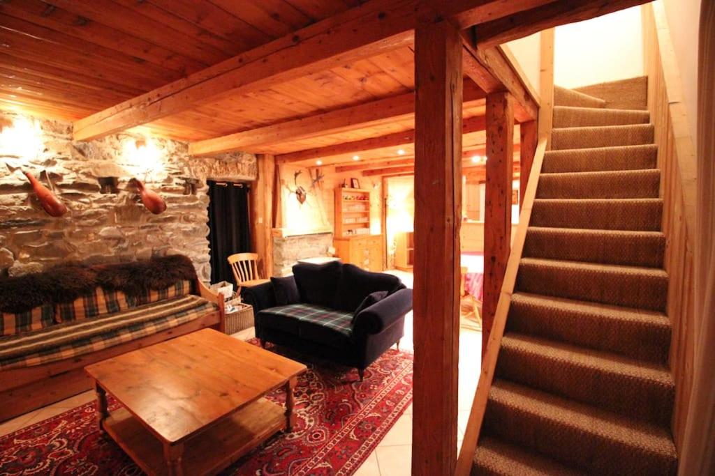 a living room with a staircase and a couch at Atmospheric, original stone chalet in Meribel in Les Allues