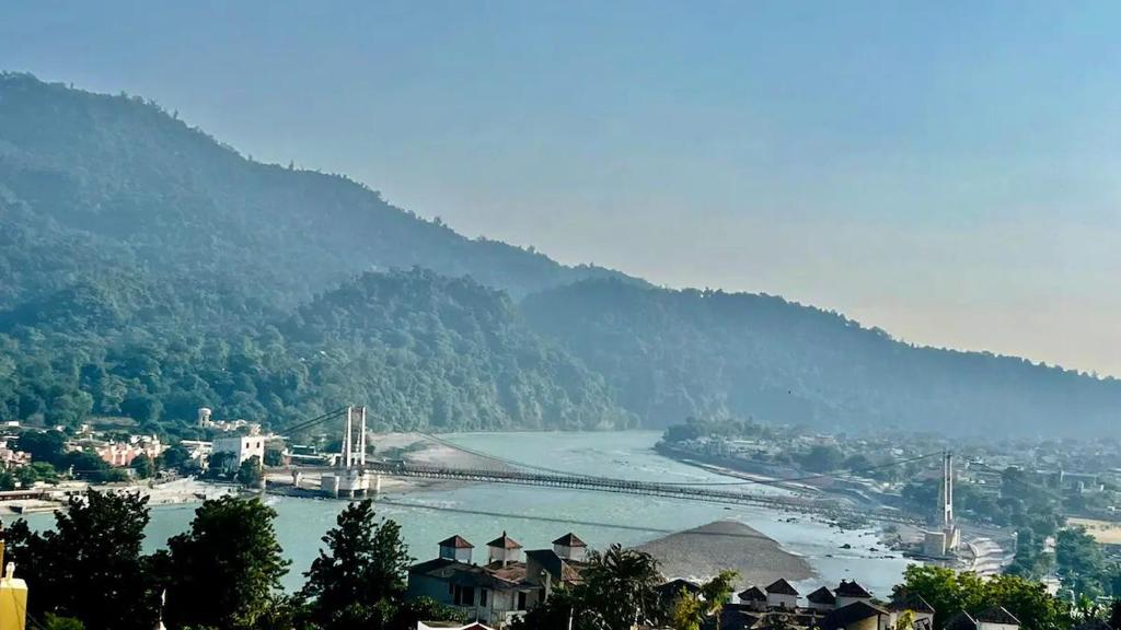 - une vue sur une rivière avec un pont et une ville dans l'établissement Luxe Ganga view Villa with Terrace Seating (Vacaow), à Rishikesh
