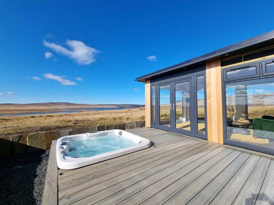 a hot tub on a deck next to a house at Torran Cottage - Views, Exclusivity & Tranquility in Halkirk