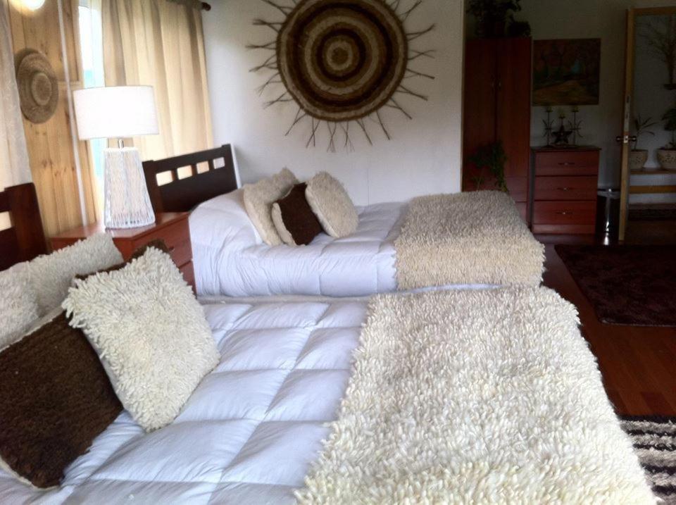 um quarto com uma grande cama branca com almofadas em Lodge Guarida del Trauco em Puqueldón