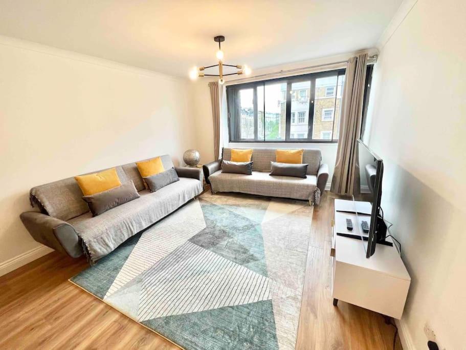 ein Wohnzimmer mit einem Sofa und einem TV in der Unterkunft LUXstay 2BR Earls Court Apartment Sleeps up to 10 in London