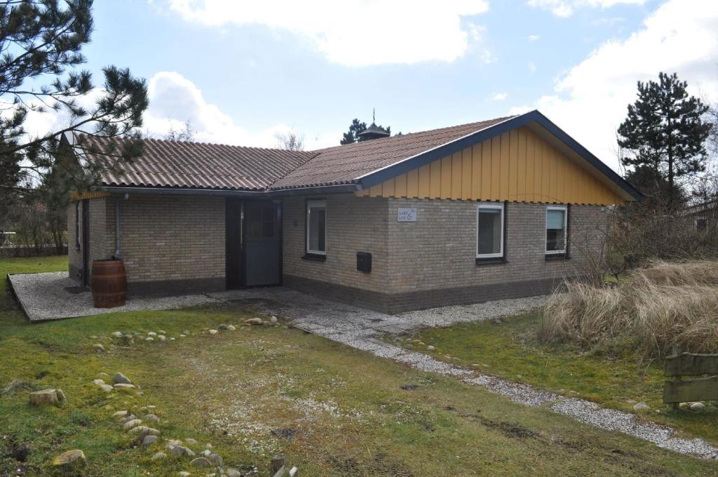 une petite maison en briques avec une cour dans l'établissement Ferienhaus "Wad und Wal" mit Schwimmbad, à Ballum