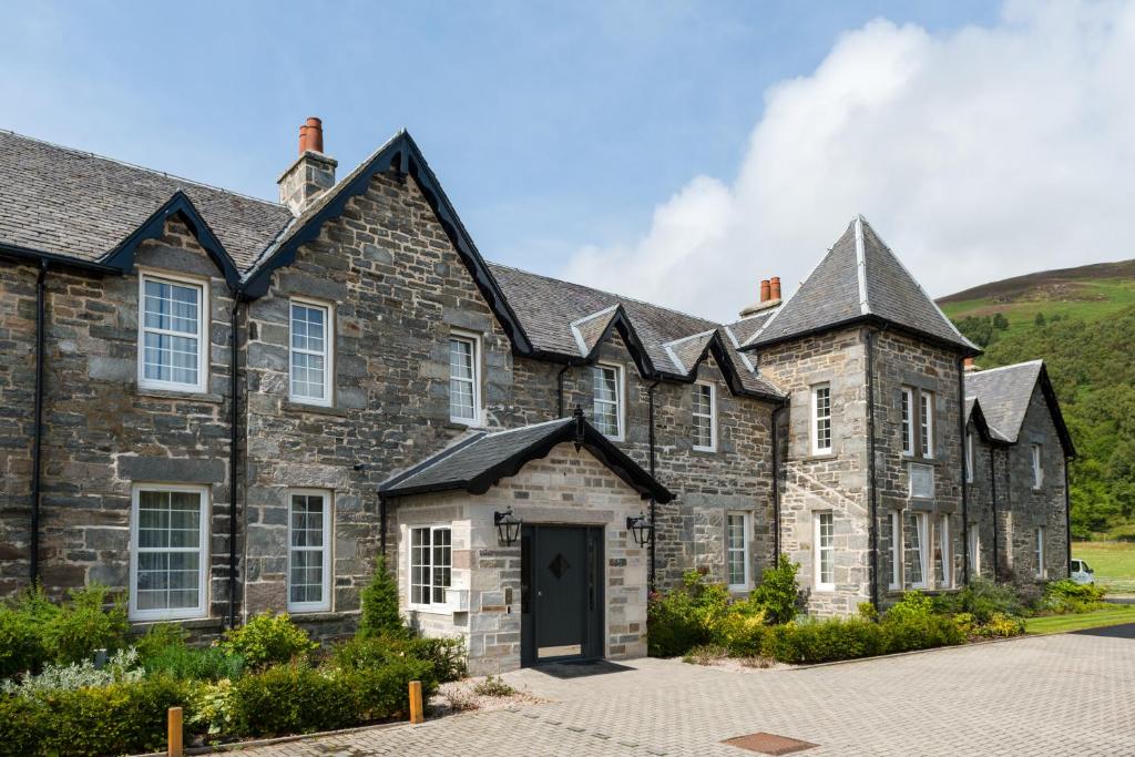 um antigo edifício de pedra com uma porta preta em Dunalastair Hotel Suites em Kinloch Rannoch