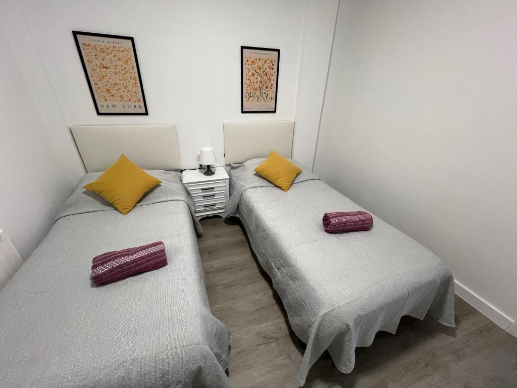 two twin beds in a small room withermottermott at Piso Camino de Santiago in Sarria