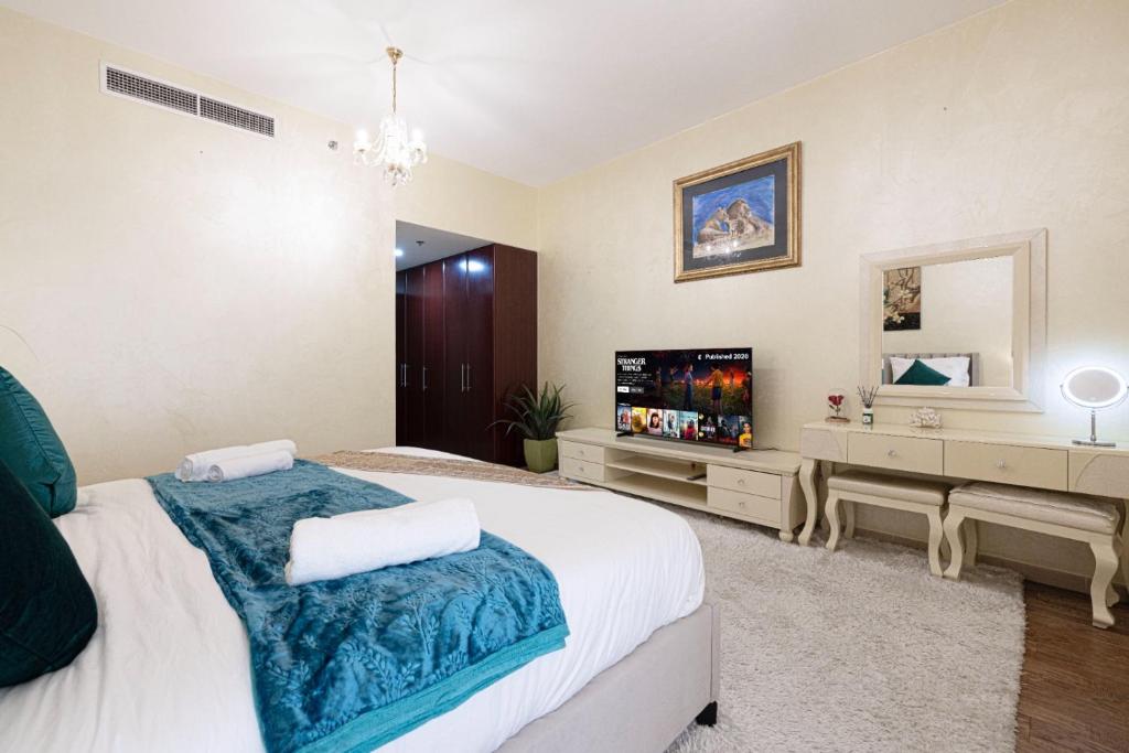 a bedroom with a large bed and a flat screen tv at Stylish and Sleek: Modern Well-Furnished One Bedroom Hall and Kitchen Apartment in Dubai