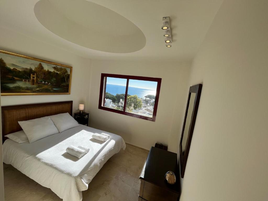 een slaapkamer met een bed met witte lakens en een raam bij Casares dream penthouse in Bahia de Casares