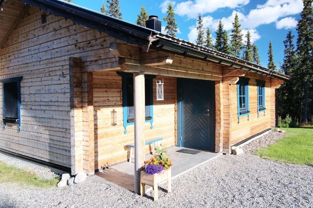 uma cabana de madeira com uma porta e flores num banco em Charmantes modernes Blockhaus mit Kamin em Galåbodarna