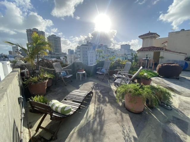 a balcony with a bench and chairs on a building at Fresh Tropical Colonial Style Walk-Up- Rooftop Terrace- Beach View in San Juan