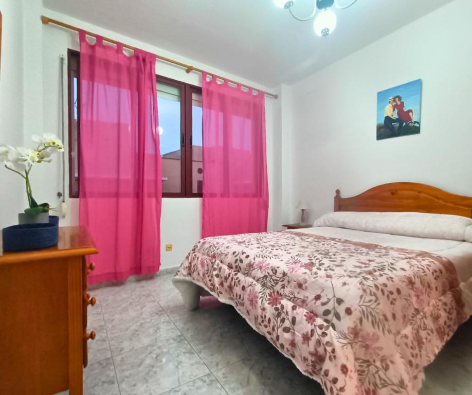 Breña AltaにあるAmanecer Las Breñasのピンクのカーテンと大型ベッドが備わるベッドルーム1室が備わります。