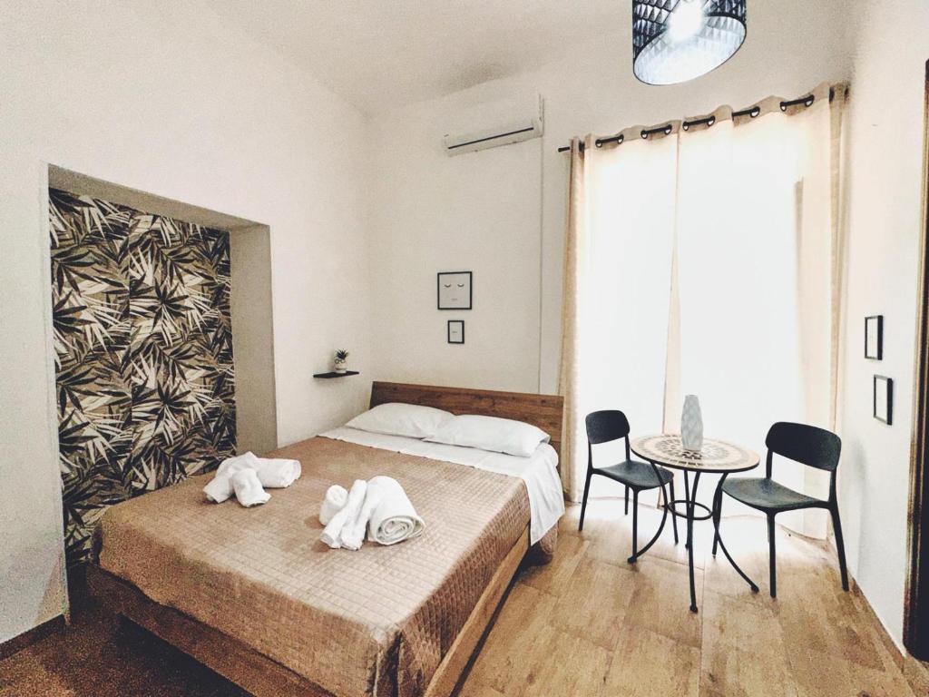 a bedroom with a bed and a table and chairs at Monteleone rooms in Palermo