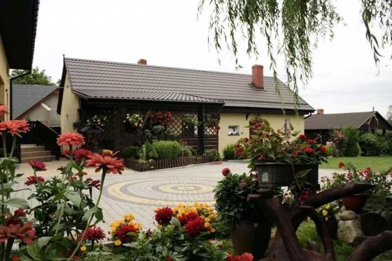 una casa con un jardín con flores delante en Agrodębina, en Nowa Słupia
