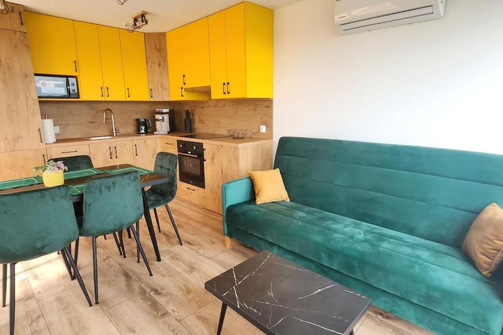 ein Wohnzimmer mit einem grünen Sofa und einer Küche in der Unterkunft Domki Skalne Miasto, Sokołowsko z balią i sauną in Mieroszów