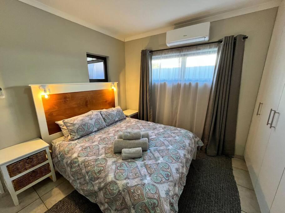een slaapkamer met een bed met een stoel erop bij Die Mossienes in Windhoek