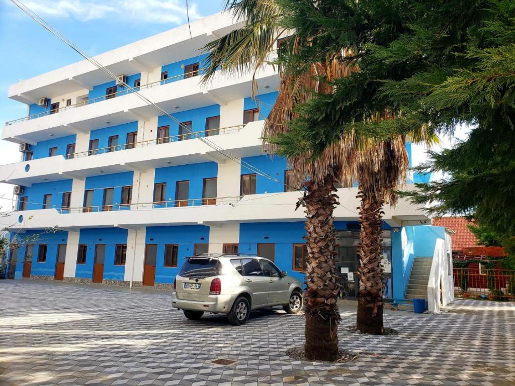 a car parked in front of a blue and white building at Hotel Rozafa Velipoje in Baks-Rrjoll
