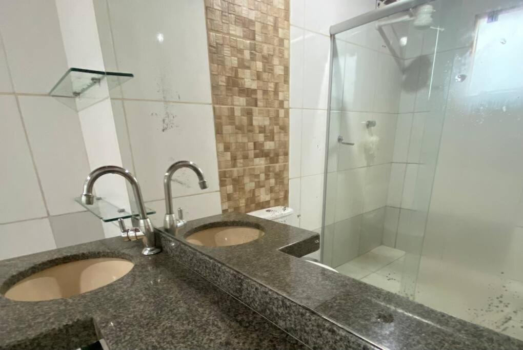 a bathroom with two sinks and a glass shower at Casa em Luís Eduardo Magalhães in Luis Eduardo Magalhaes