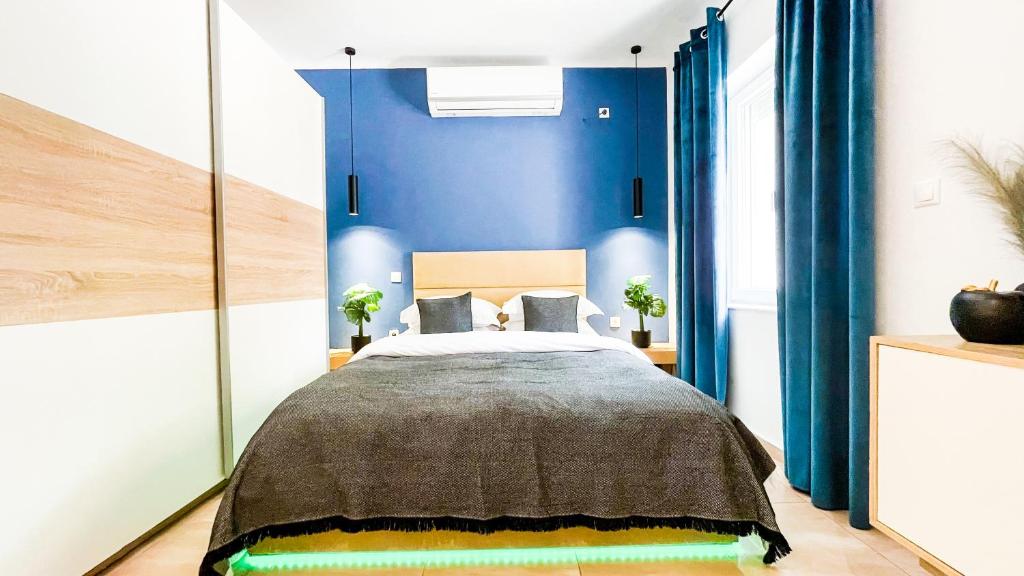 sypialnia z dużym łóżkiem z niebieskimi ścianami w obiekcie OASIS RESIDENCE w mieście Korynt
