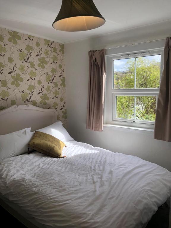 a bedroom with a bed with a window and a pillow at Komorebi Healing House in Dawlish