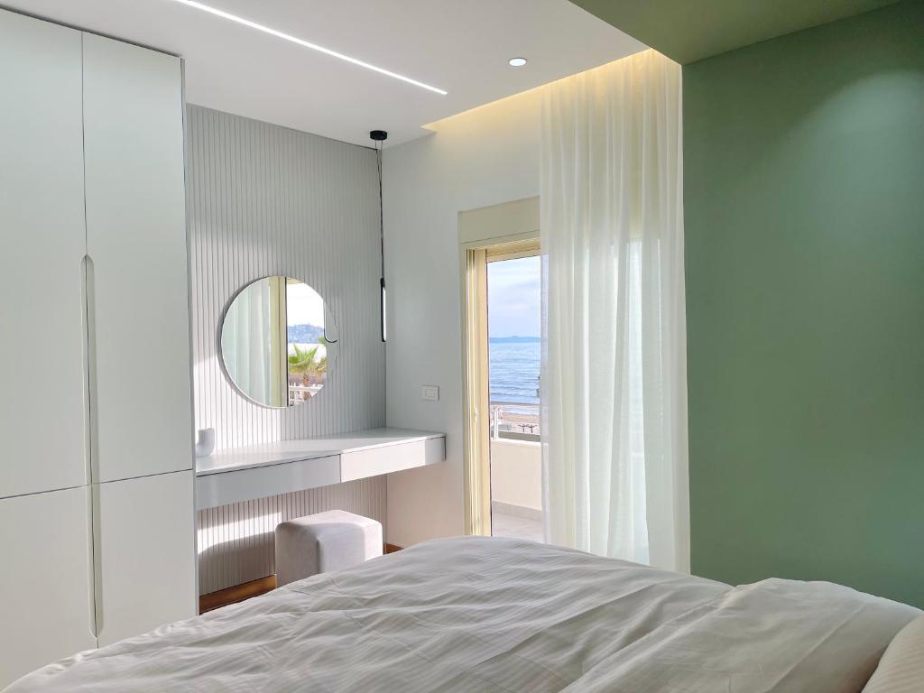 Luxurious Cozy seaview apartment في دوريس: غرفة نوم بسرير ومرآة ونافذة