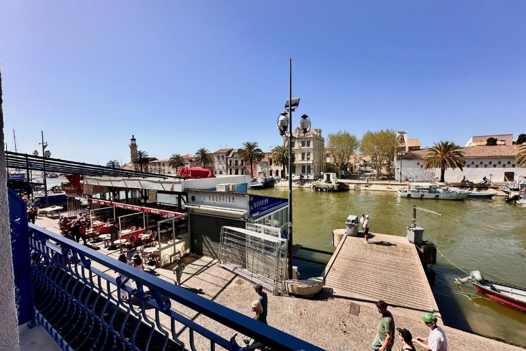 un bateau est amarré à un quai dans une rivière dans l'établissement Les Poissons - Appartement une chambre vue canal, au Grau-du-Roi