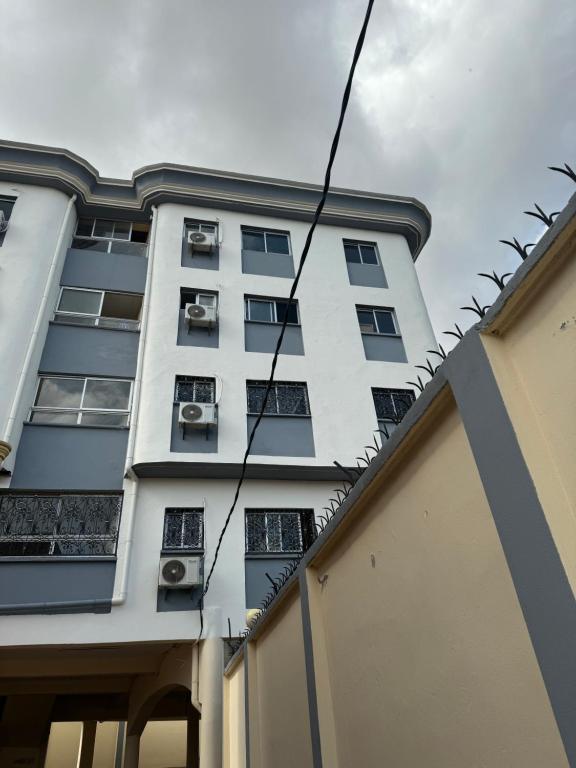 un grand bâtiment blanc avec des fenêtres et une clôture dans l'établissement Lekker Estate, à Yaoundé