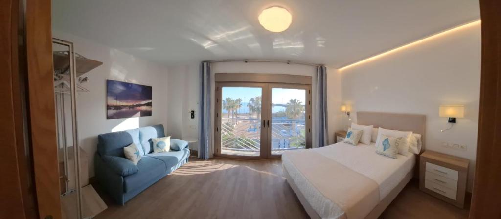 a bedroom with a large bed and a blue chair at APARTAMENTOS SAN NICOLAS in Adra