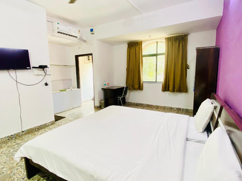 1 dormitorio con cama blanca y ventana en Budget Private Ac Room with Kitchen Near Osho Garden, en Pune