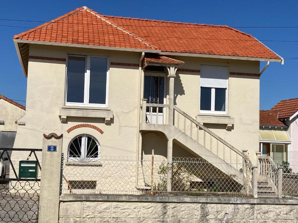 una casa con escalera y techo rojo en Les chambres du Phare en Le Port-des-Barques