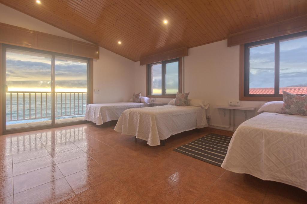 a room with three beds and windows with a view at casa picota in Oia