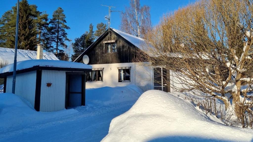 uma casa coberta de neve com um barracão em Villa Assar, Ferienhaus in der Nähe von Schwedens größten Stromschnellen em Vidsel
