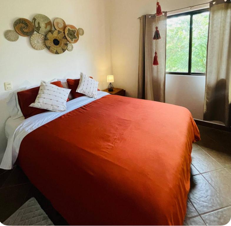 1 dormitorio con 1 cama grande de color naranja y ventana en TRANQUILA CASA DE PLAYA, en Santa Cruz