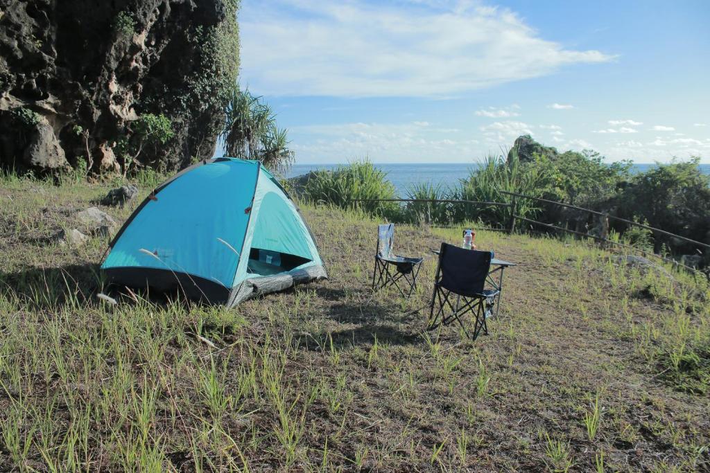 Ngandong的住宿－Wisata Alam Lestari Gunung Semar，蓝色帐篷和田野上的两把椅子