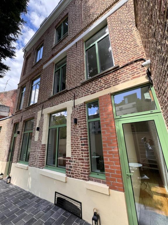 a brick building with a green door on a street at Victorias House Suite in Lille